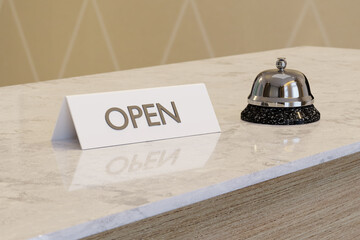 Open sign on the white marble desk of a hotel reception with a silver bell next to it