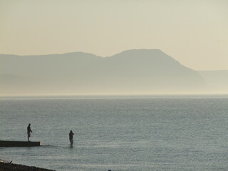 sea anglers fishing off Lyme Regis in early morning autumnal mist 