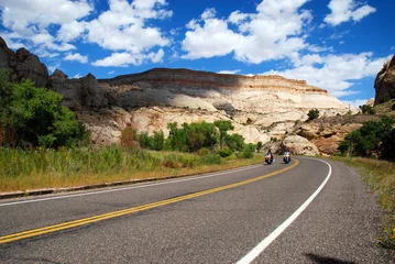 Fototapeten motorcycle riding in desert on empty highway through red rock mesa and scenic landscape © mikesch112