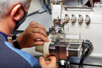 The foreman adjusts the correct operation of a modern sewing machine.