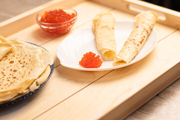 Red caviar with large white pancakes on a white plate. Traditional Russian cuisine on a holiday. Maslenitsa days.