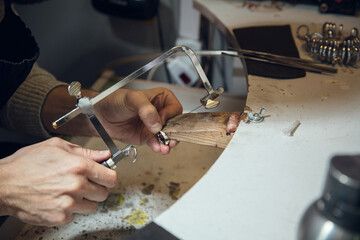 Craftsman. Close up hands of jeweller, goldsmiths making of silver ring with gemstone using...