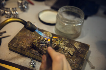Heating. Close up hands of jeweller, goldsmiths making of silver ring with gemstone using professional tools. Craft production, precious and luxury jewel, hand made occupation. Workshop, artwork.