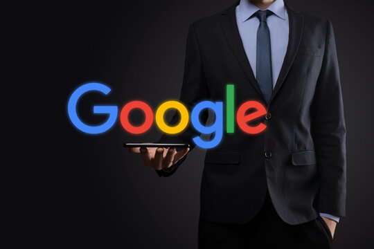 VINOGRADIV, UKRAINE - 30 DECEMBER 2020. Businessman in a suit on a dark background holds a Google logo inscription. Google is world's most popular search engine