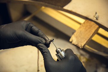 Accuracy. Close up hands of jeweller, goldsmiths making of silver ring with gemstone using...