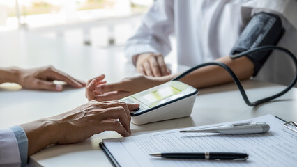 Doctor measuring patient blood pressure in clinic or hospital office. Medical and Health concept.