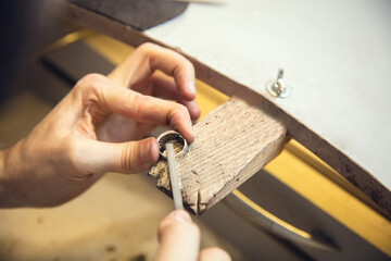 Polishing. Close up hands of jeweller, goldsmiths making of silver ring with gemstone using professional tools. Craft production, precious and luxury jewel, hand made occupation. Workshop, artwork.