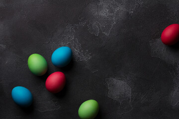 Fototapeta na wymiar Easter eggs on black textured background, top view, space