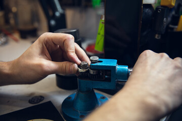 Leveling. Close up hands of jeweller, goldsmiths making of silver ring with gemstone using professional tools. Craft production, precious and luxury jewel, hand made occupation. Workshop, artwork.