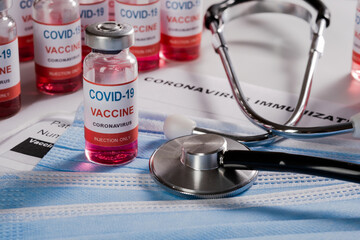 new coronavirus infection vaccine, stethoscope and clean medical mask placed on immunization document 