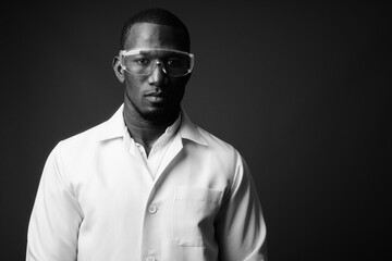 Handsome African man doctor wearing protective glasses against brown background