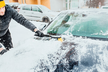 Morning snow removal - a man cleans the car before the trip - cold start in winter