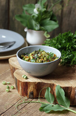 Vegan protein meal, dish of assorted stewed green legume vegetables: peas, green bean, broccoli garnished with parsley and flower petals, closep, vertical, vegan food concept