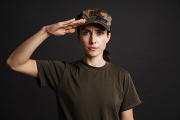 Confident beautiful soldier woman saluting and looking at camera