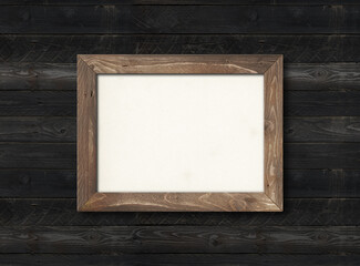 Old rustic wooden picture frame hanging on a black wall. Horizontal picture