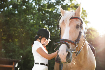 Young woman in horse riding suit and her beautiful pet outdoors on sunny day