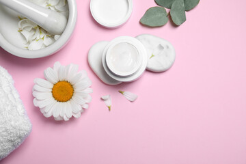 Flat lay composition with chamomile flower and cream on pink background. Space for text