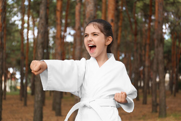 Cute little girl in kimono practicing karate in forest © New Africa