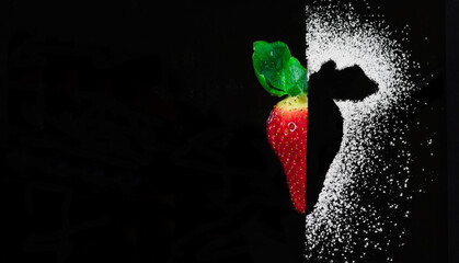 Fresa cortada por la mitad con fondo negro y silueta de az&uacute;car