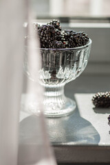 Fresh juicy blackberry macro photography. Blackberry in a glass bowl close up. Blackberry in a transparent vase on the table. Ready-to eat.