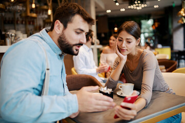 Young happy couple using smartphone in cafe