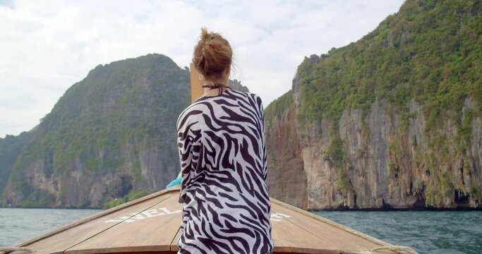 young woman sailing on the boat through the waves to amazing Phi Phi island
