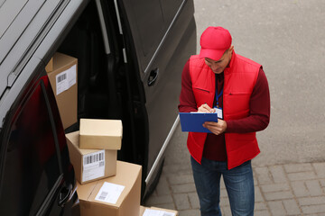 Courier checking amount of parcels in delivery van outdoors