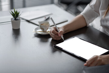 Business woman Join a meeting offer creativity by taking notes using the tablet at the office. Blank white screen. Mock up.