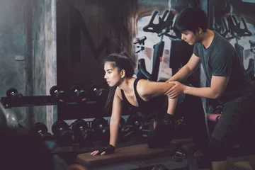 Gordijnen Asian man personal trainer with exercise equipment, dumbbells with Asian woman at the gym. © amnaj