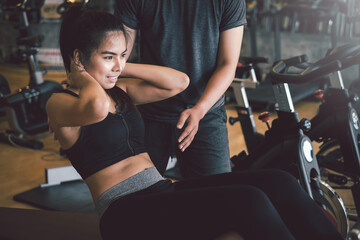 Fototapeta na wymiar Asian woman work out with a personal trainer doing sit ups to stay healthy at the gym.