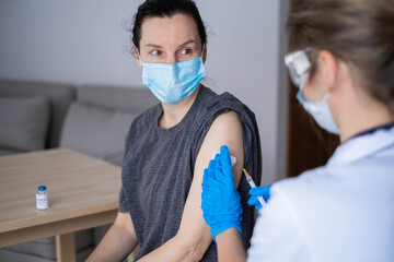 Fototapeta na wymiar Doctor in personal protective suit or PPE inject vaccine shot to stimulating immunity of woman patient at risk of coronavirus infection. Coronavirus,covid-19 and vaccination concept