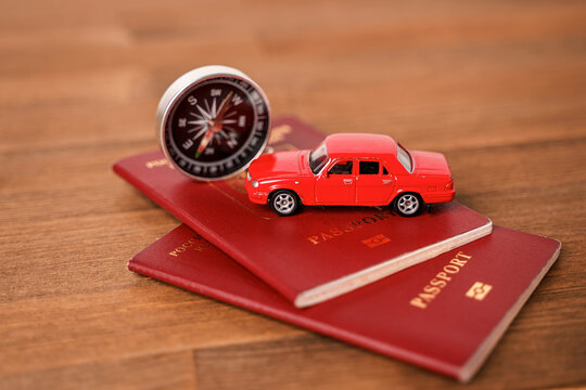 A toy car on foreign passports and a compass. Tourist composition on a wooden table