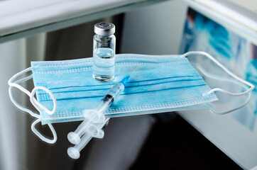 Ampoules and syringe with Covid-19 vaccine on a laboratory table.For the prevention, immunization and treatment of coronavirus infection.Infectious medicine concept. With copy space
