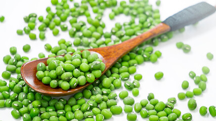 Green Mung Beans in spoon. Scattered green grains of Mung Beans on a white background. Healthy vegetarian food. Food background concept.