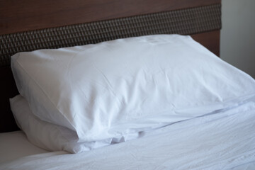 Stack of white soft pillows on comfortable bed sheet