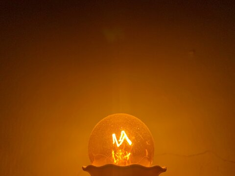 Yellow light bulb lit in the dark