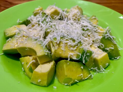 Chopped avocado with milk cream and cheese on a green plate
