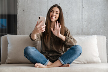 Cheerful brunette nice girl waving hand and using mobile phone