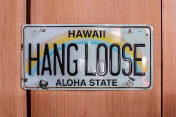 February 2021: Hang Loose Hawaii Aloha State License Plate tacked up against a cedar wall, Ontario,...