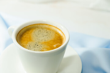 
white cup of coffee on blue cloth