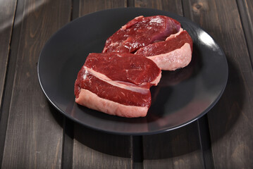 Raw beef steak for cooking on a plate on the kitchen desk.