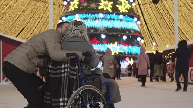 Young woman in a wheelchair and her boyfriend at Christmas party on the streets