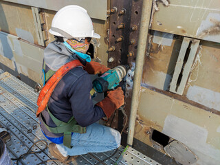 Workers are using a Impact Wrench to torque bolts to hold the splice plate with steel girder at splice joint of steel structure work.