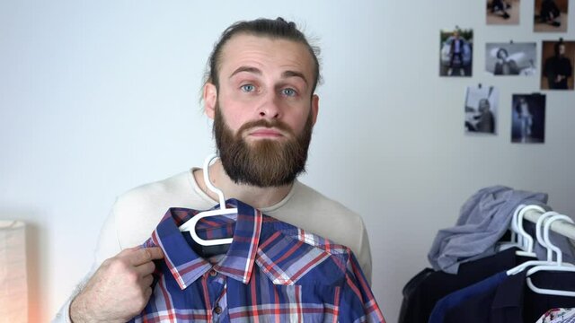 Attractive young guy is looking into the mirror Putting together outfit with new shirt
