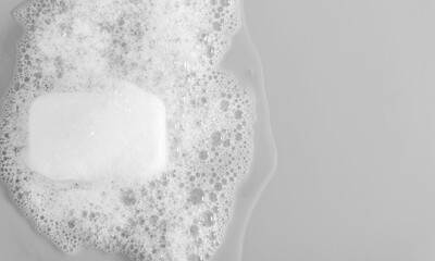 White soap bar and foam on gray background. Flat lay, top view, copy space