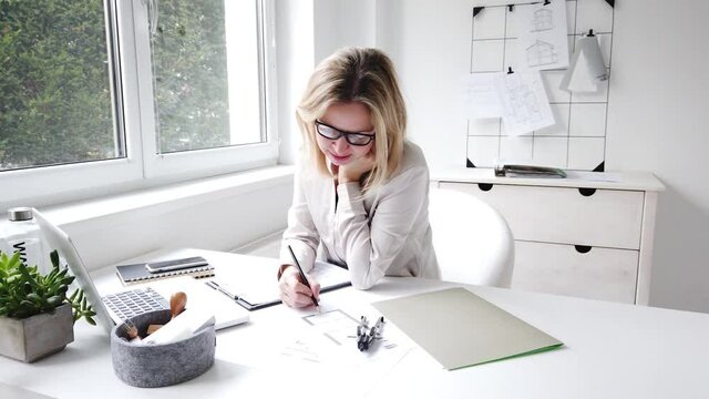 beautiful. female architect is sitting in her office and doing web meeting via laptop