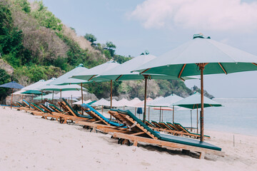 Beach resort. A lot of sun loungers and umbrellas along the sea. Expensive island vacation.