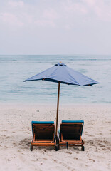 Specially set for two: sun loungers and umbrella on the first line. Honeymoon, vacation by the sea. Island. 