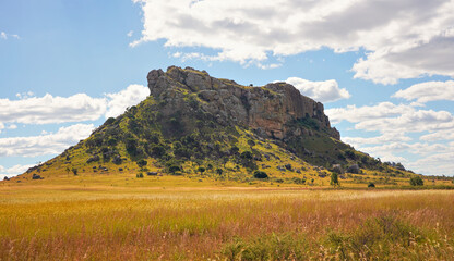 Low grass growing on African savanna, small rocky mountains in background - typical scenery at...