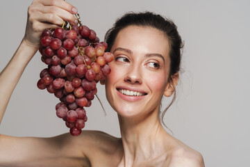 Smiling half-naked woman posing with bunch of grapes